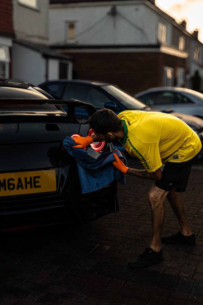 Cris working on the rear of a black Nissan GT-R as the sun sets behind the houses