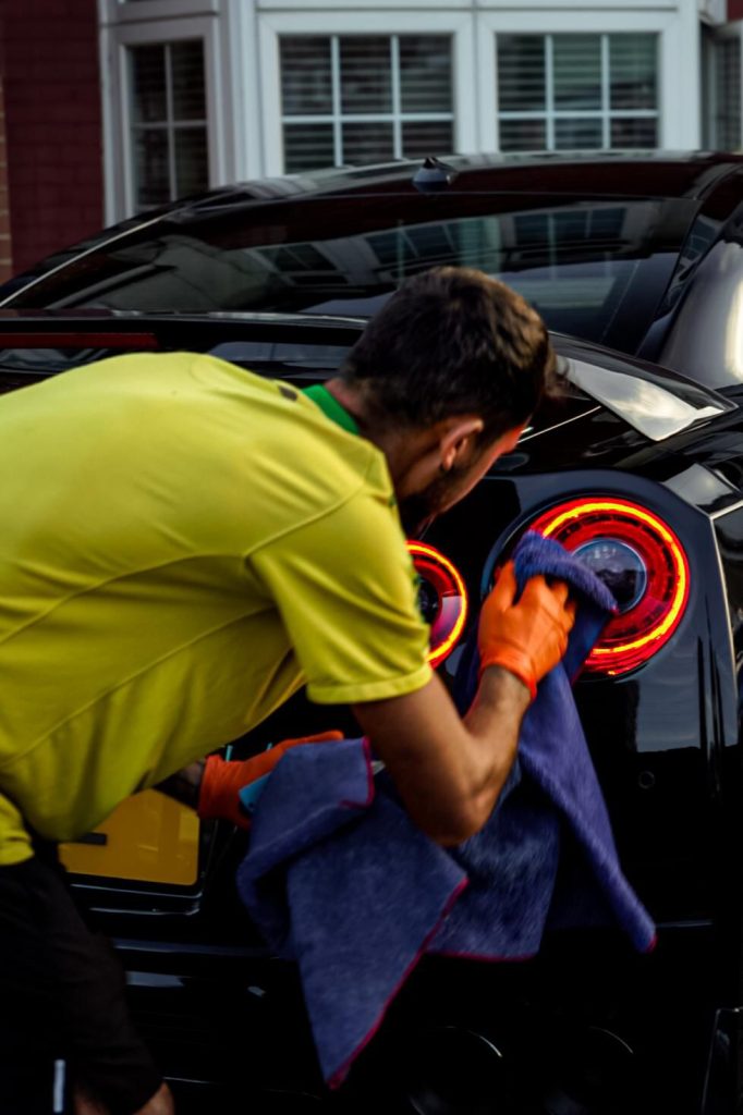 Close-up of Cris buffing a glowing round Nissan GT-R tail light with a microfibre towel