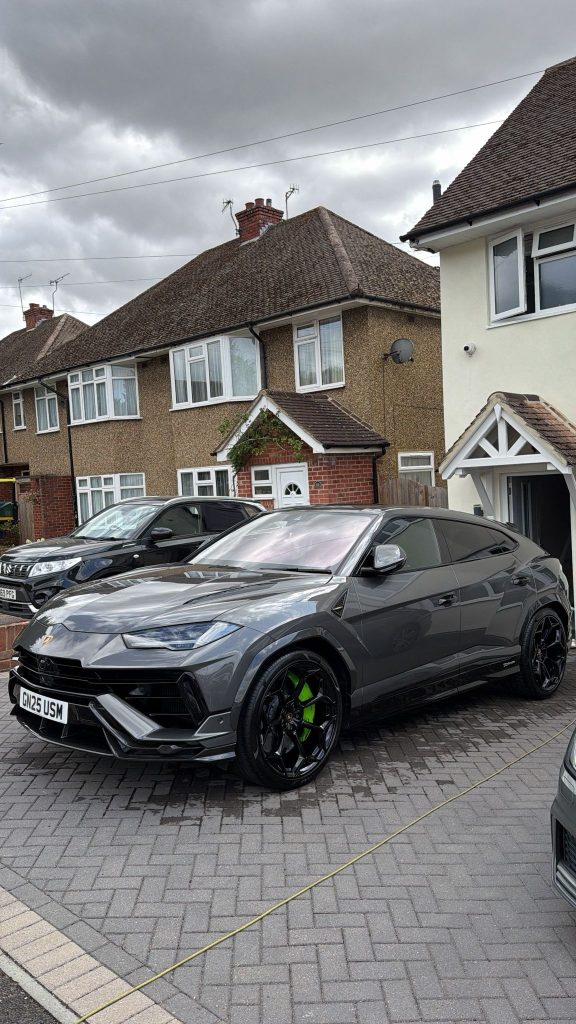 Gunmetal grey Lamborghini Urus with green brake calipers, freshly detailed on a block-paved driveway