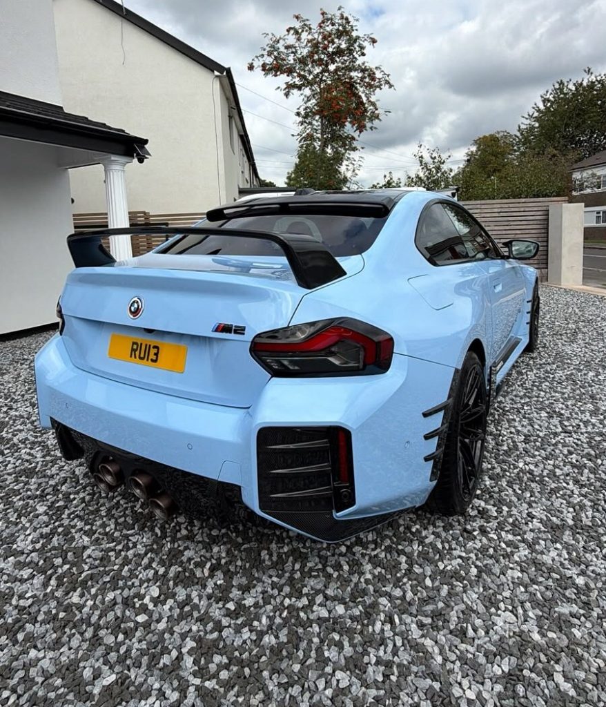 Rear of a light blue BMW M2 with carbon wing and quad exhausts after a detail
