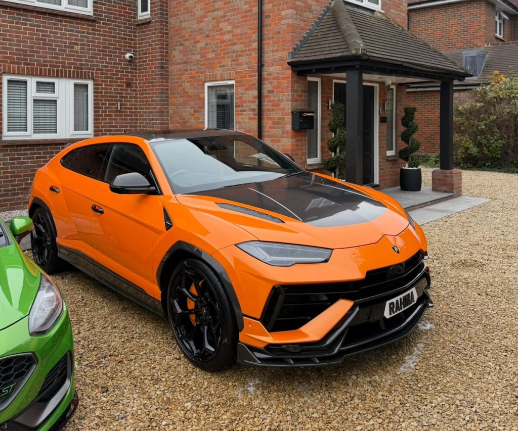 Orange Lamborghini Urus with a carbon bonnet on a gravel driveway after a detail